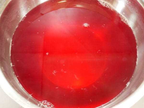 ボウルに濾した液体にレモン汁を加えると鮮やかな色に変わった赤紫蘇ジュースの画像。