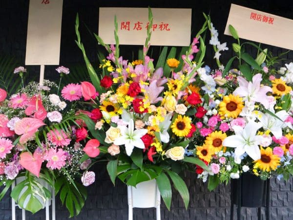 色とりどりの花が飾られている開店祝いのスタンド花が3つ並んでいる画像。