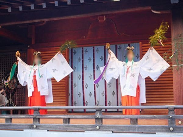 京都・城南宮のお涼み信じで笹を手に持って神楽舞を舞う二人の巫女の画像。