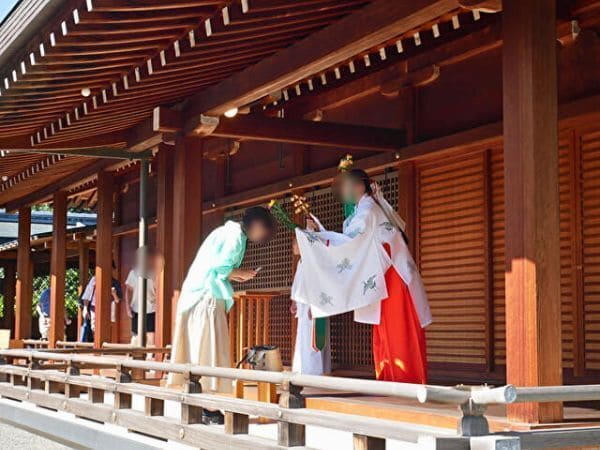 京都・城南宮の菊の巫女神楽の後、参拝者が手に持ったお守りを巫女が神楽鈴で祓っている画像。