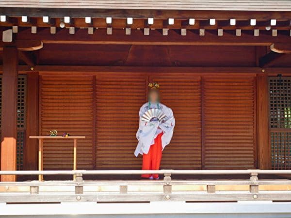 京都・城南宮の菊の巫女神楽の扇の舞で扇の銀色の面を見せながら舞う巫女。