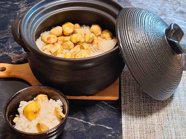 土鍋で炊いた栗ご飯とそれを焦げ茶色の素朴な焼き物の器に盛った写真。