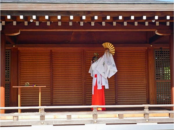 京都・城南宮の菊の巫女神楽の扇の舞で扇の金色の面を見せながら舞う巫女。